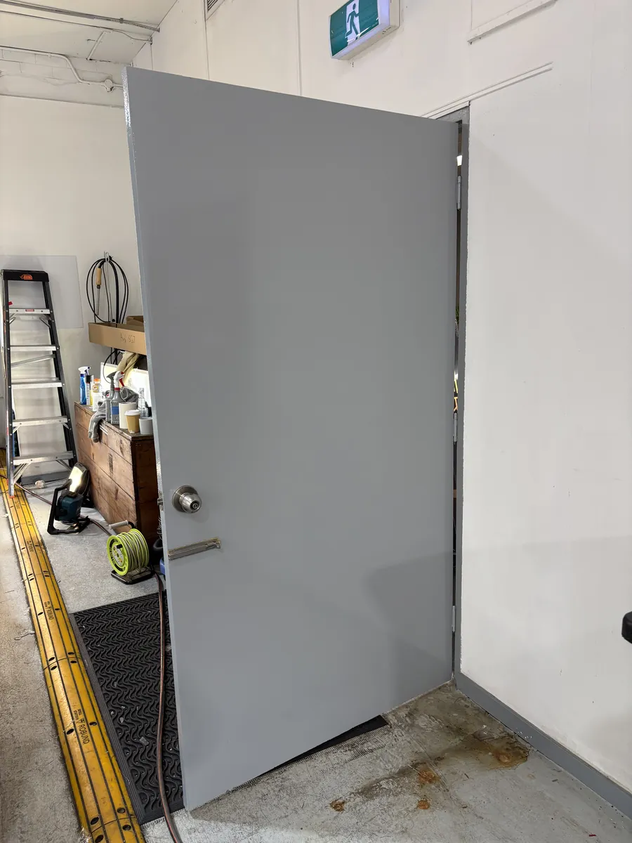Freshly painted door rehung in its frame, tools and ladder nearby