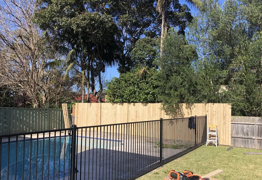 Pool fence with a newly built timber paling fence behind it