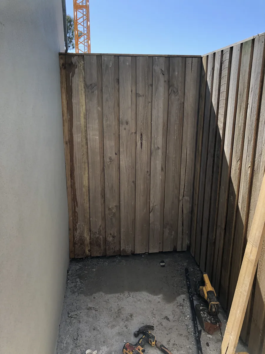 Narrow side courtyard with a new timber fence panel and a rendered wall