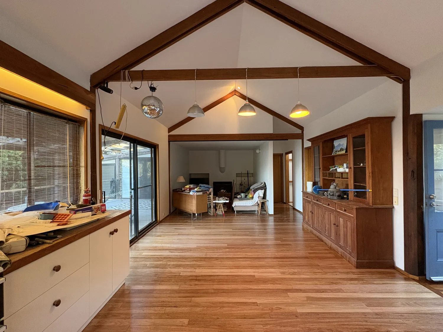 Open-plan living room with timber floors and exposed beams after a repaint